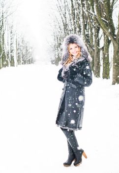 Woman is walking in park alley in winter