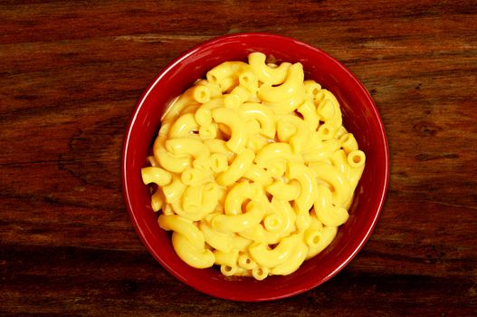 mac and cheese - cheesy pasta in red bowl on wood background