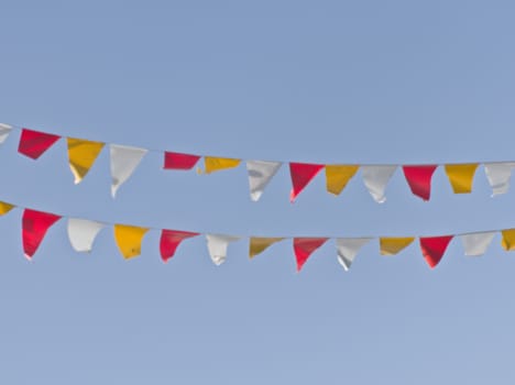 Two rows of colorful triangular flags occur against a background of blue sky