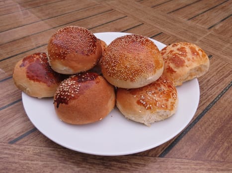 On a white plate neatly laid out round buns with sesame and poppy seeds                          