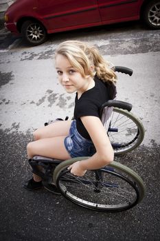 Cute disabled girl riding a wheelchair on the road