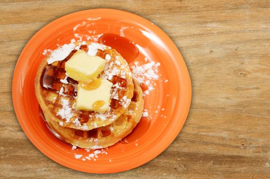 waffles with butter and syrup on wood background