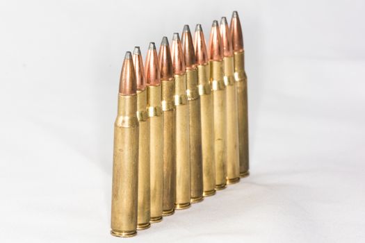 A few rifle bullets lined up in a row on white background