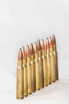 A few rifle bullets lined up in a row on white background