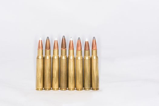 A few rifle bullets lined up in a row on white background