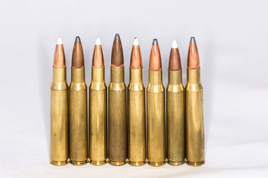 A few rifle bullets lined up in a row on white background