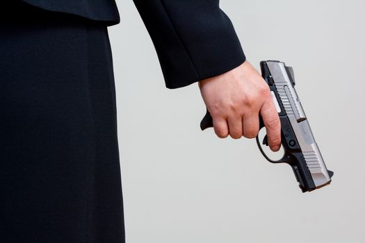 Close up of a the back side of a woman in business suit holding a hand gun