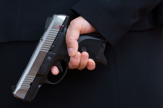 Close up with woman in business suit hold a pistol to dark suit 