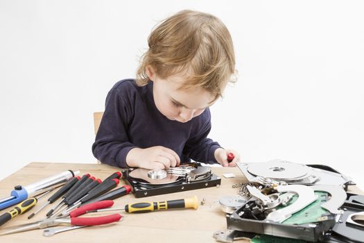 young child repairing open hard disk drive with different tools