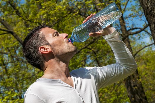 Man is drinking water against a natural background