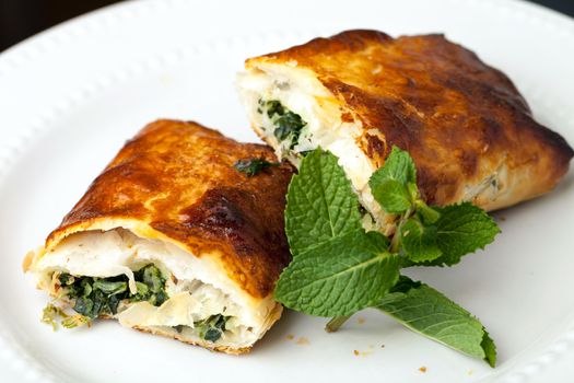 Greek spanakopita or spinach pie on a white plate.  Shallow depth of field.