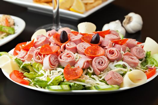 A delicious looking tossed chefs salad or antipasto with meat cheese and kalamata olives.