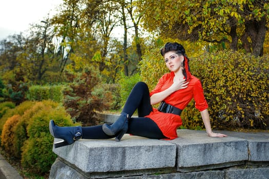 Attractive young girl in a red shirt walks in the city park