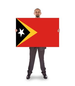 Smiling businessman holding a big card, flag of East Timor