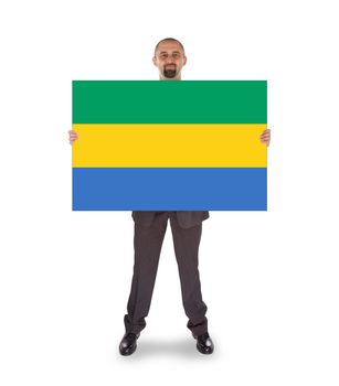 Smiling businessman holding a big card, flag of Gabon
