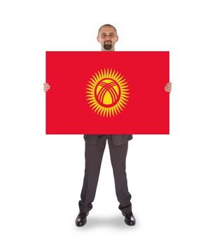 Smiling businessman holding a big card, flag of Kyrgyzstan