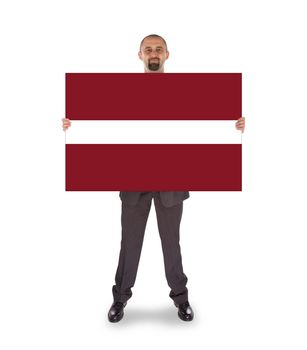 Smiling businessman holding a big card, flag of Latvia