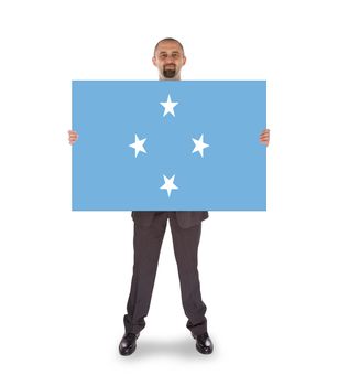 Smiling businessman holding a big card, flag of Micronesia