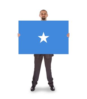 Smiling businessman holding a big card, flag of Somalia