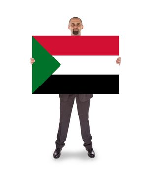 Smiling businessman holding a big card, flag of Sudan