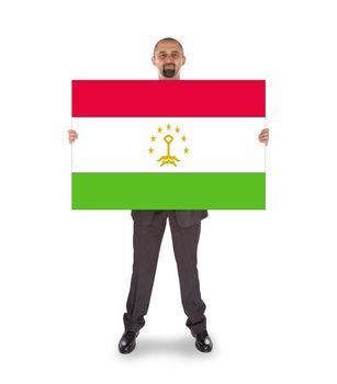 Smiling businessman holding a big card, flag of Tajikistan