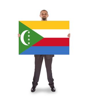 Smiling businessman holding a big card, flag of The Comoros