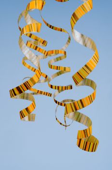 Arrangement of Four Striped Yellow Curly Hanging Party Streamers isolated on Blue background