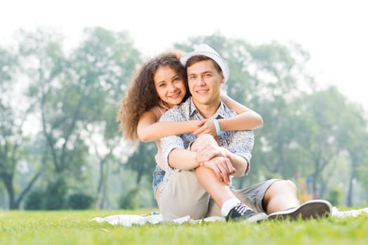 romantic couple lying on the grass in the summer park, spending time with loved ones