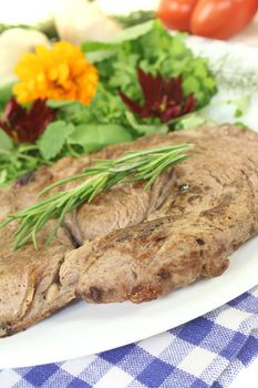 Sirloin steak with wild herb salad and rosemary on a light background