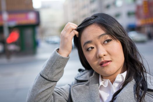 Young Asian woman in coat on a street in a large city