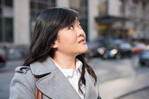 Young Asian woman in coat on a street in a large city