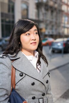 Young Asian woman in coat on a street in a large city