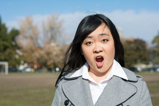 Outdoor portrait of young woman looking surprised