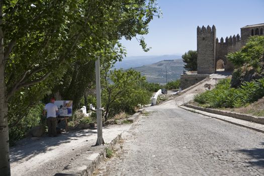 Tower of the Barbacana and painter under the shade of a fig tree, Sabiote, Jaen province, Andalusia, Spain