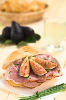 Fresh fig slices on smoked ham sandwich garnished with chives on sandwich paper (Selective Focus, Focus on the middle of the sandwich)