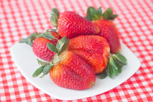 strawberries in bowl on checkered fabric