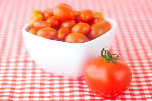 cherry tomatos and tomatos in bowl on checkered fabric