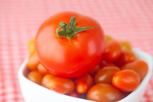 cherry tomatos and tomatos in bowl on checkered fabric