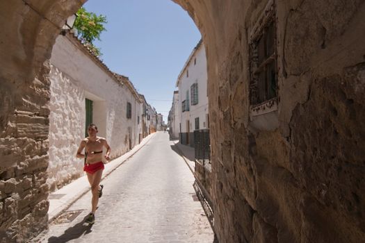 Runner passing a arabic door in a street of Sabiote, Jaen province, Andalusia, Spain