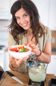 Portrait of a girl using the blender to prepare raw banana ice cream with strawberries