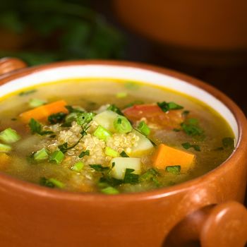 Vegetarian quinoa soup with carrot, potato, celery, leek and tomato, sprinkled with parsley and scallion (Selective Focus, Focus one third into the soup)