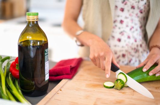 Detail of a girl using a ceramic knife to cut zucchini