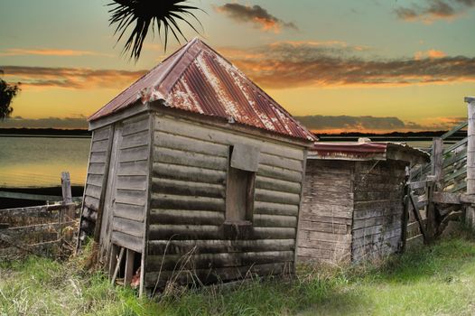 Old rundown and dilapidated huts by the water at sunset.