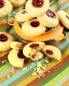 Broken jam biscuits in front of a jam jar on a napkin.