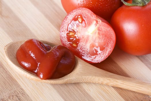Ketchup in a spoon and fresh red tomatoes