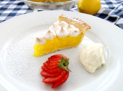 Delightful slice of lemon meringue pie with strawberries and cream.