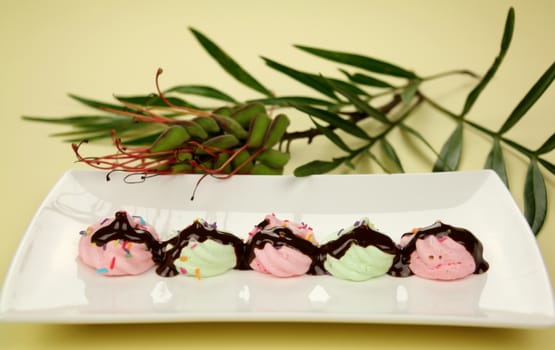 A line of chocolate mini meringues on a plate ready to serve.