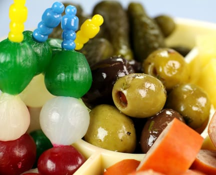 Pickle onions and olives in a plate of finger food.