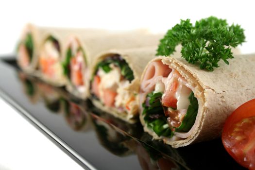 Mixed platter of delicious ham and chicken salad wraps.