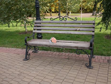 Wedding bouquet of roses on a wooden bench in the park